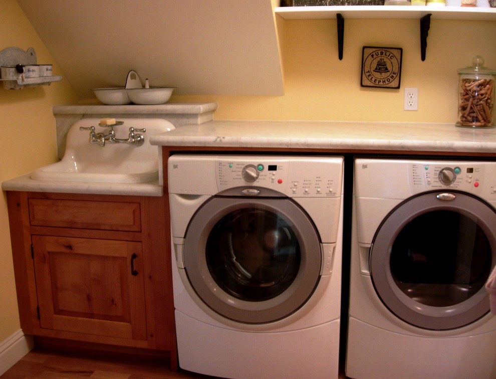 Inspiration for a mid-sized timeless single-wall light wood floor dedicated laundry room remodel in San Francisco with a drop-in sink, raised-panel cabinets, medium tone wood cabinets, marble countertops, yellow walls and a side-by-side washer/dryer
