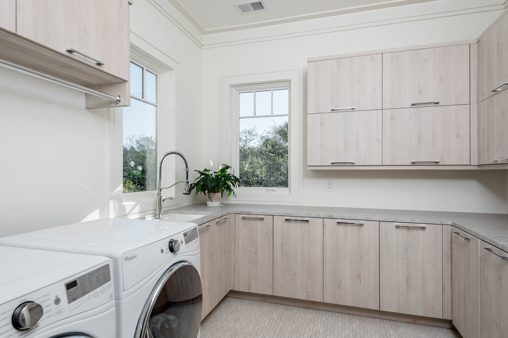 Idéer för att renovera en mellanstor funkis grå u-formad grått tvättstuga enbart för tvätt, med en undermonterad diskho, släta luckor, skåp i ljust trä, vita väggar, en tvättmaskin och torktumlare bredvid varandra, beiget golv, bänkskiva i kvartsit och klinkergolv i porslin