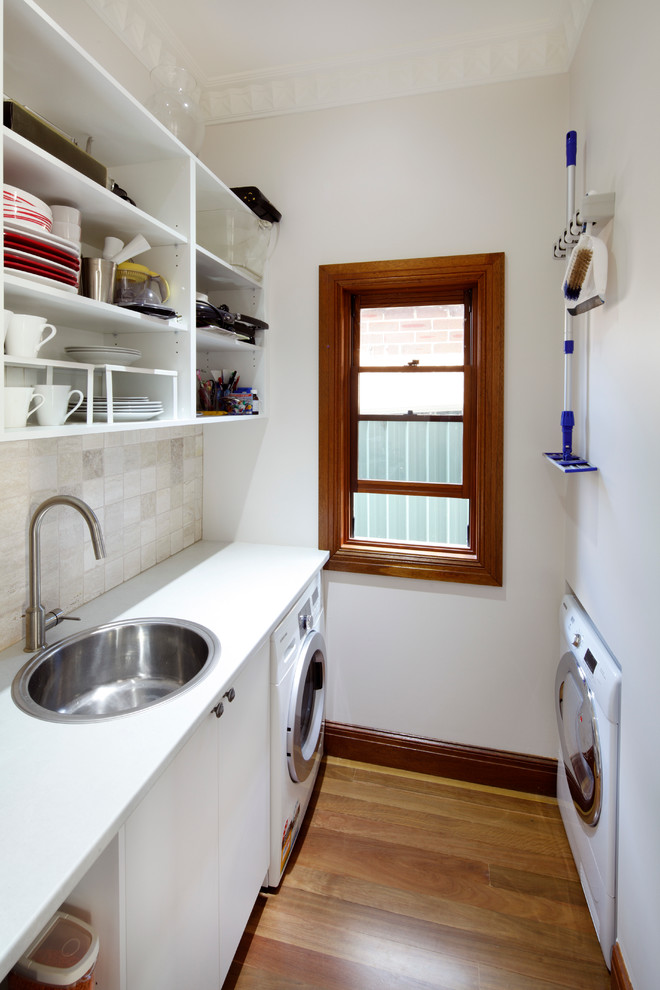 Example of a small classic galley medium tone wood floor utility room design in Sydney with a drop-in sink, flat-panel cabinets, white cabinets, white walls and white countertops