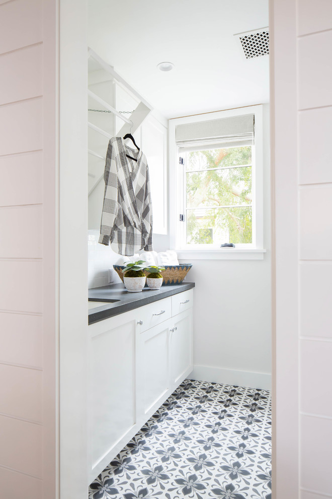 Esempio di una sala lavanderia country di medie dimensioni con lavello sottopiano, ante in stile shaker, ante bianche, pareti bianche, lavatrice e asciugatrice affiancate e pavimento grigio