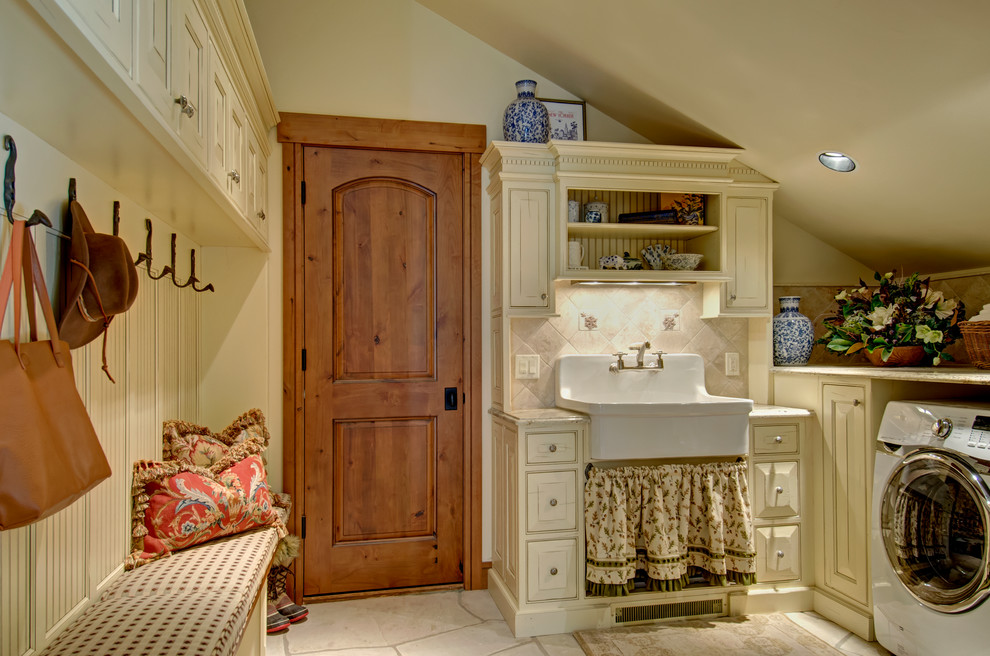 Exemple d'une buanderie chic dédiée avec un évier de ferme, un placard à porte affleurante, des portes de placard beiges, un mur beige et un sol beige.