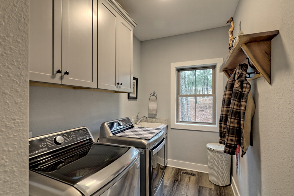Immagine di una sala lavanderia stile americano di medie dimensioni con lavello da incasso, ante in stile shaker, ante grigie, top in granito, pareti grigie, pavimento in vinile, lavatrice e asciugatrice affiancate, pavimento grigio e top bianco