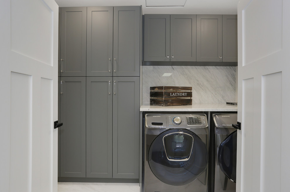 Immagine di un ripostiglio-lavanderia design di medie dimensioni con ante in stile shaker, ante grigie, top in marmo, pareti bianche e lavatrice e asciugatrice affiancate