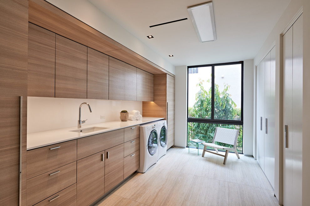 Design ideas for a contemporary separated utility room in Miami with a submerged sink, flat-panel cabinets, a side by side washer and dryer, beige floors, white worktops and medium wood cabinets.