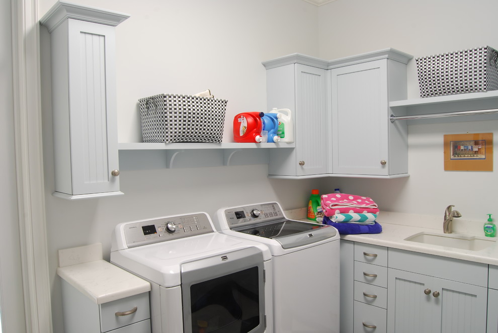 Photo of a medium sized beach style u-shaped utility room in Cincinnati with shaker cabinets, a side by side washer and dryer, white cabinets and a submerged sink.