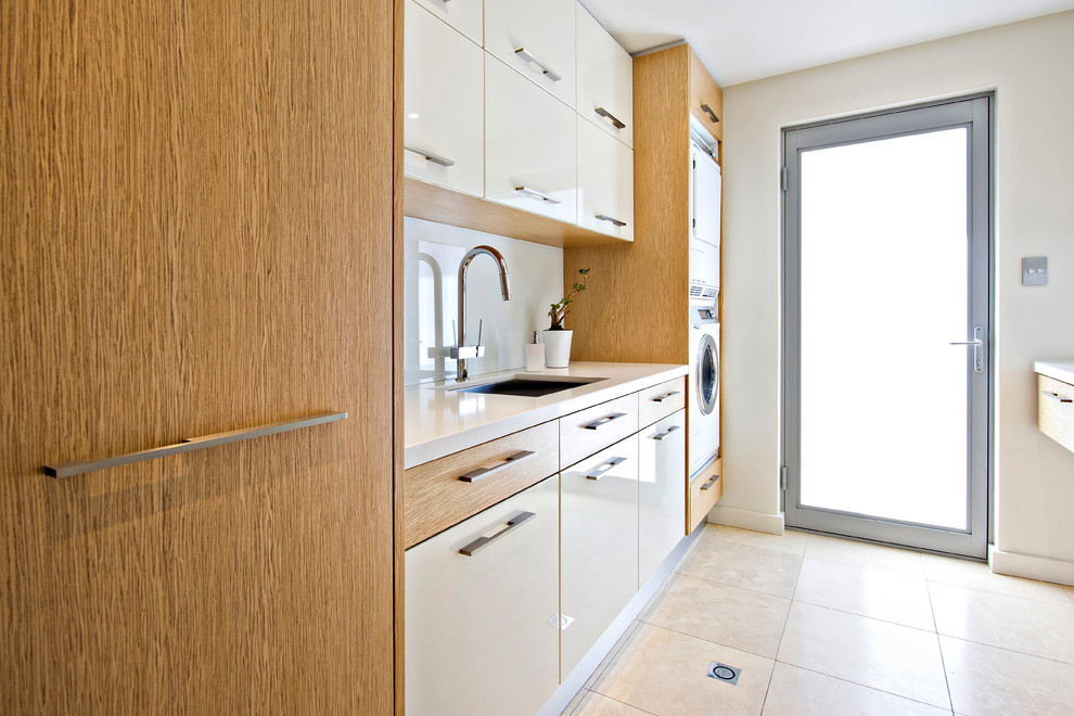 Contemporary galley separated utility room in Perth with a built-in sink, flat-panel cabinets, white cabinets, granite worktops, white walls, ceramic flooring and a stacked washer and dryer.