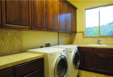 Inspiration för stora moderna l-formade tvättstugor enbart för tvätt, med en nedsänkt diskho, luckor med infälld panel, skåp i mörkt trä, marmorbänkskiva, beige väggar, travertin golv och en tvättmaskin och torktumlare bredvid varandra