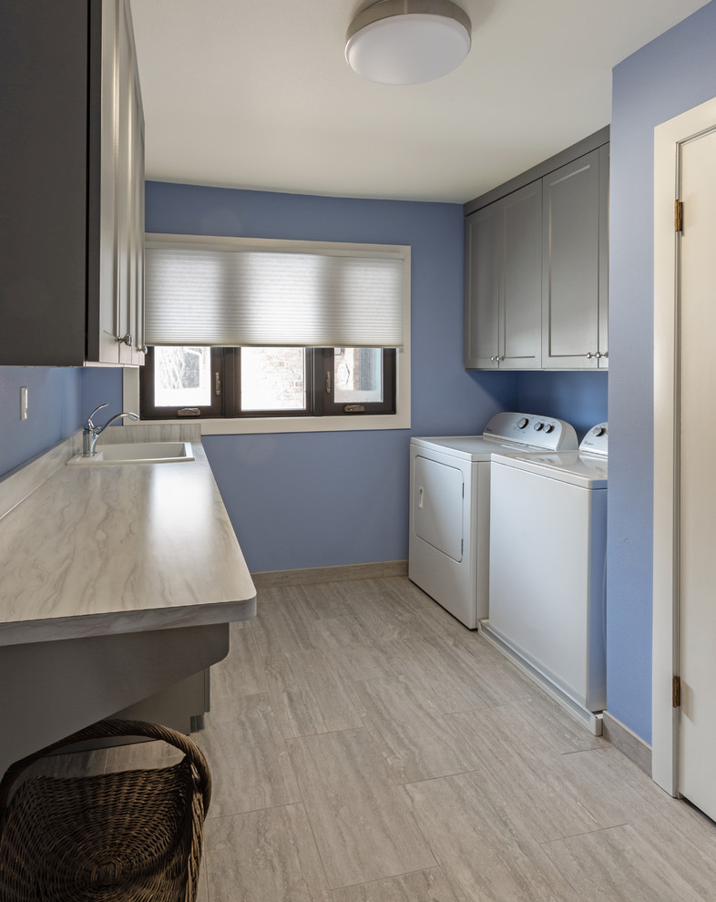 Example of a mid-sized eclectic galley porcelain tile and gray floor dedicated laundry room design in Milwaukee with a drop-in sink, recessed-panel cabinets, gray cabinets, laminate countertops, blue walls, a side-by-side washer/dryer and gray countertops