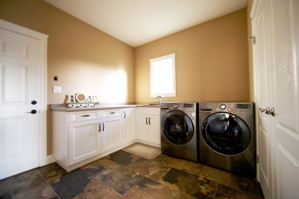 Modelo de cuarto de lavado lineal tradicional con fregadero encastrado, armarios estilo shaker, puertas de armario blancas, lavadora y secadora juntas y paredes marrones