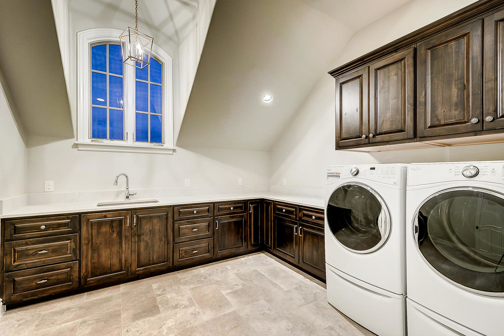 Large elegant l-shaped porcelain tile and beige floor dedicated laundry room photo in Denver with an undermount sink, raised-panel cabinets, dark wood cabinets, marble countertops, white walls, a side-by-side washer/dryer and beige countertops