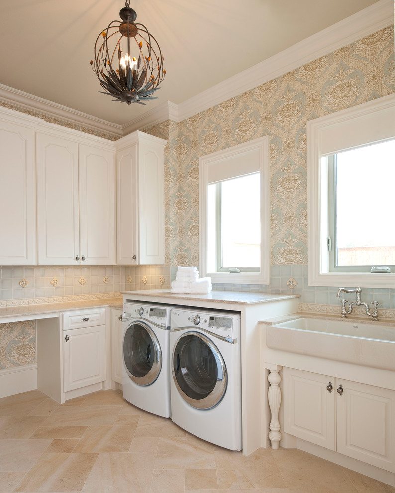 Inredning av en klassisk mycket stor l-formad tvättstuga enbart för tvätt, med en rustik diskho, luckor med upphöjd panel, vita skåp, bänkskiva i kalksten, kalkstensgolv, en tvättmaskin och torktumlare bredvid varandra och flerfärgade väggar