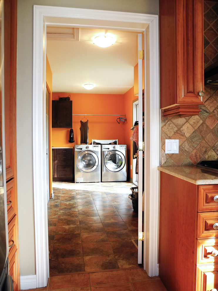 Multifunktionaler, Einzeiliger, Großer Moderner Hauswirtschaftsraum mit Schrankfronten mit vertiefter Füllung, dunklen Holzschränken, Waschmaschine und Trockner nebeneinander, Einbauwaschbecken und oranger Wandfarbe in Ottawa