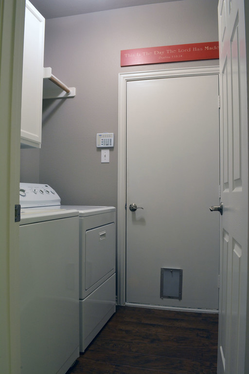 Foto di una lavanderia moderna di medie dimensioni con ante bianche, top in granito e pavimento in vinile