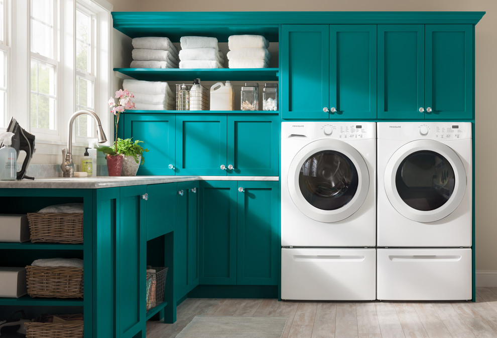 Kleine Moderne Waschküche in L-Form mit Unterbauwaschbecken, blauen Schränken, Granit-Arbeitsplatte, beiger Wandfarbe, hellem Holzboden, Waschmaschine und Trockner nebeneinander und Schrankfronten im Shaker-Stil in New York