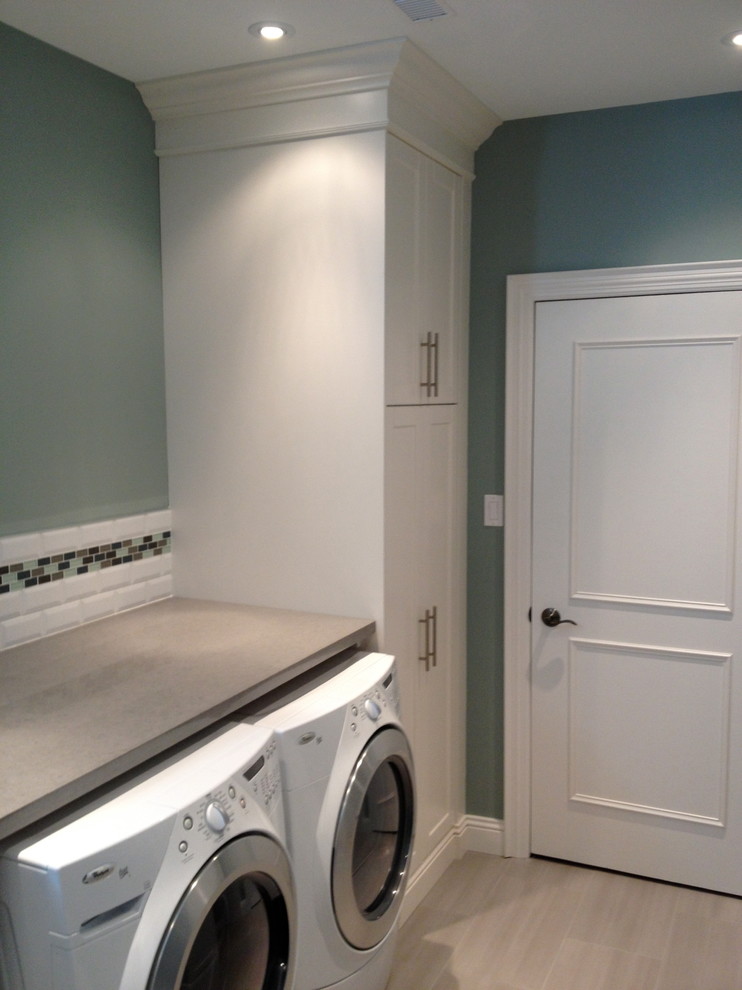 Photo of a medium sized contemporary single-wall separated utility room in Toronto with flat-panel cabinets, white cabinets, laminate countertops, blue walls, light hardwood flooring and a side by side washer and dryer.