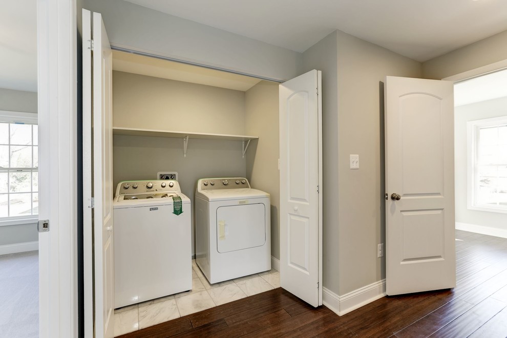 Modelo de cuarto de lavado de galera clásico renovado pequeño con armarios con puertas mallorquinas, paredes grises, suelo de baldosas de cerámica, lavadora y secadora juntas y suelo blanco