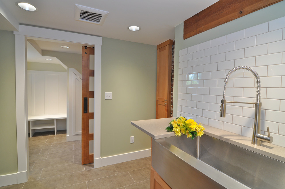 Mid-sized arts and crafts porcelain tile dedicated laundry room photo in Seattle with a farmhouse sink, shaker cabinets, medium tone wood cabinets, quartz countertops, green walls and a stacked washer/dryer