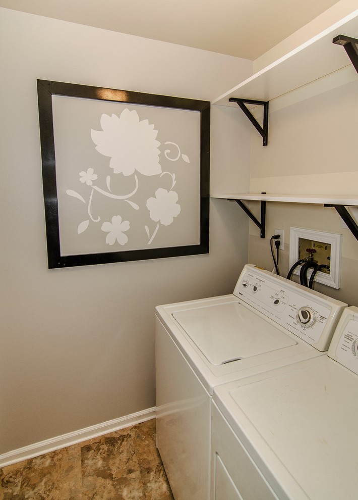Modelo de cuarto de lavado tradicional renovado pequeño con paredes grises, suelo vinílico y lavadora y secadora juntas