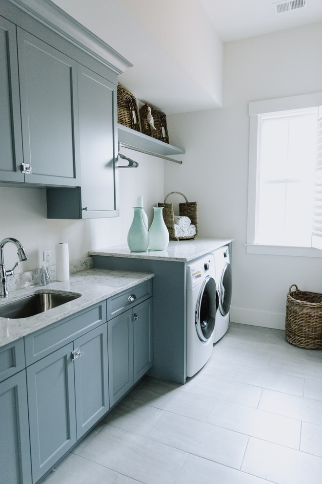 Bild på en stor vintage grå parallell grått tvättstuga enbart för tvätt och med garderob, med en undermonterad diskho, skåp i shakerstil, blå skåp, bänkskiva i kvarts, vita väggar, klinkergolv i porslin och vitt golv