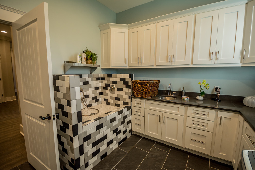 This is an example of a medium sized traditional utility room in Nashville with a submerged sink, shaker cabinets, beige cabinets, blue walls, porcelain flooring, a side by side washer and dryer and black floors.