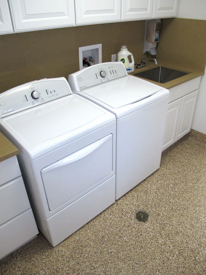 Esempio di una sala lavanderia chic di medie dimensioni con lavello sottopiano, ante con bugna sagomata, ante bianche, top in superficie solida, pareti beige, pavimento in vinile e lavatrice e asciugatrice affiancate