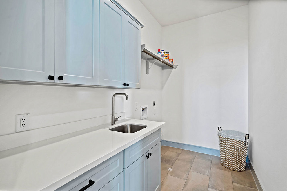 Esempio di una lavanderia chic di medie dimensioni con ante grigie, pareti bianche, pavimento in gres porcellanato e pavimento grigio