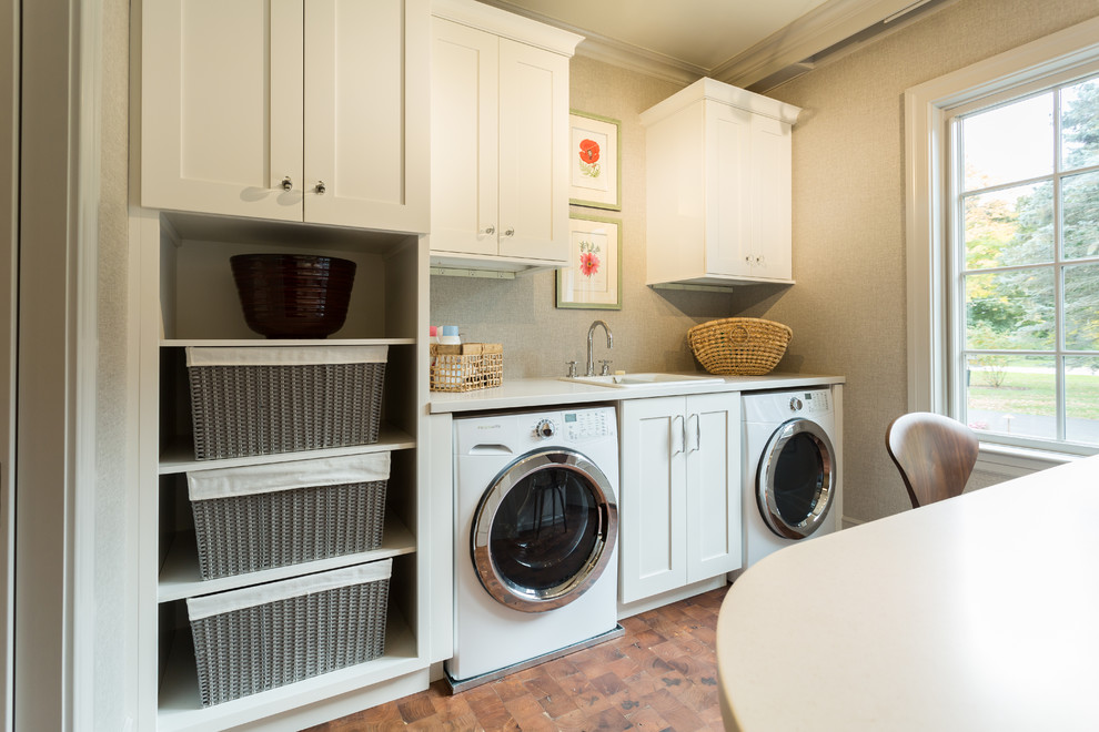 Photo of a large traditional u-shaped utility room in Milwaukee with a built-in sink, recessed-panel cabinets, white cabinets, composite countertops, grey walls, a side by side washer and dryer and medium hardwood flooring.