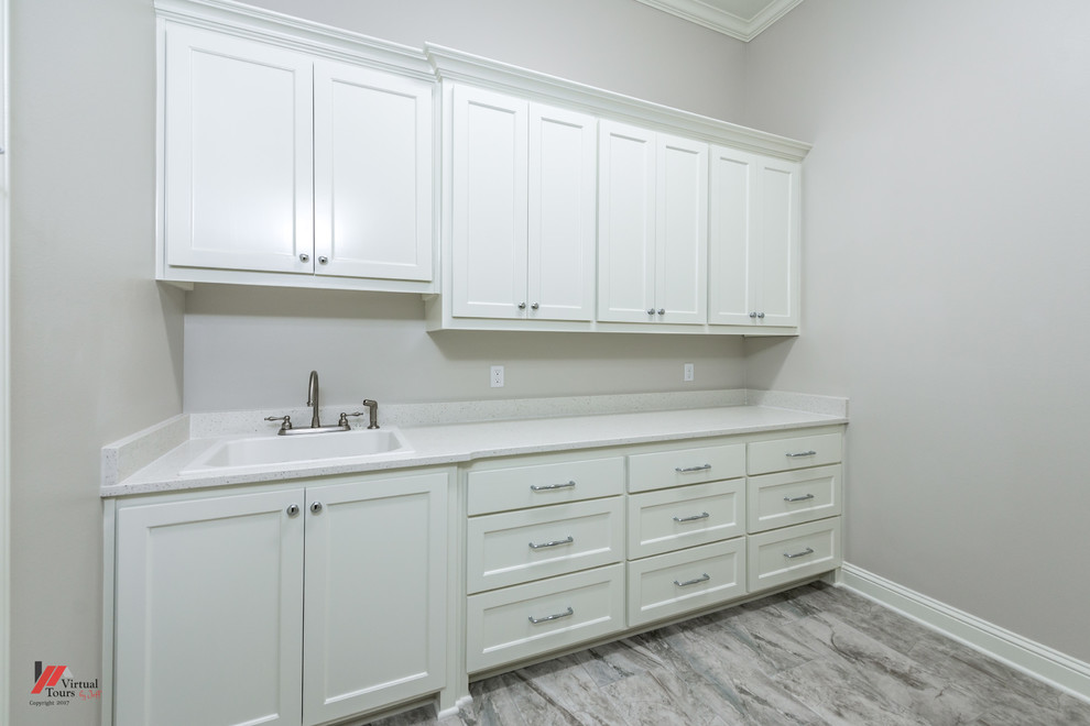 ニューオリンズにある中くらいなトラディショナルスタイルのおしゃれな洗濯室 (白いキャビネット、グレーの壁、左右配置の洗濯機・乾燥機、グレーの床、白いキッチンカウンター) の写真