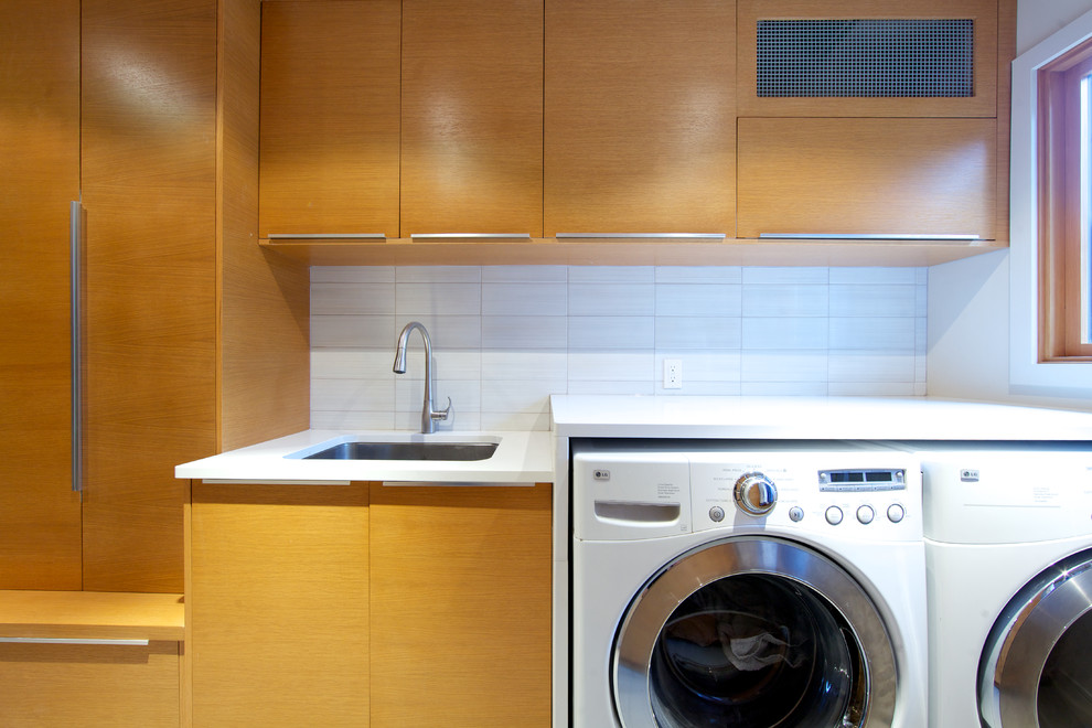 Idéer för en stor modern parallell tvättstuga enbart för tvätt, med en undermonterad diskho, släta luckor, skåp i ljust trä, vita väggar, klinkergolv i keramik och en tvättmaskin och torktumlare bredvid varandra
