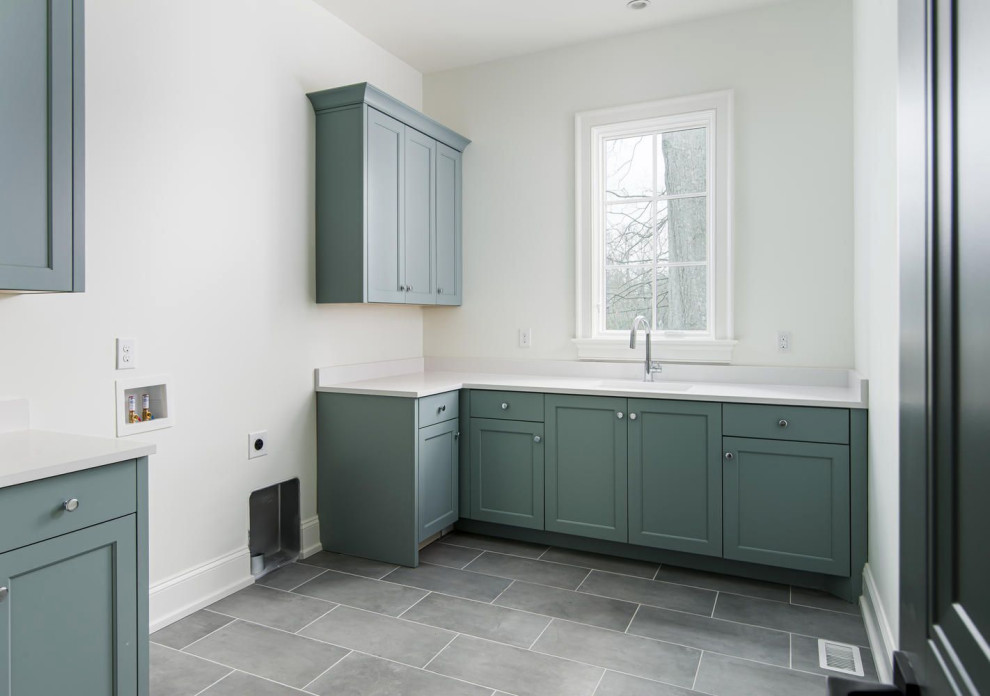 Large transitional l-shaped porcelain tile and gray floor dedicated laundry room photo in Nashville with a single-bowl sink, shaker cabinets, blue cabinets, quartz countertops, white walls, a side-by-side washer/dryer and white countertops