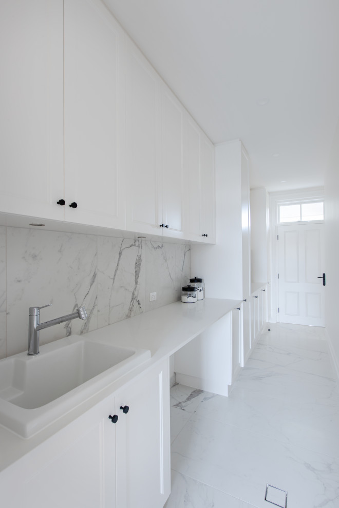 Design ideas for a large classic single-wall utility room in Adelaide with a single-bowl sink, shaker cabinets, white cabinets, engineered stone countertops, white walls, porcelain flooring, a side by side washer and dryer, white floors and white worktops.