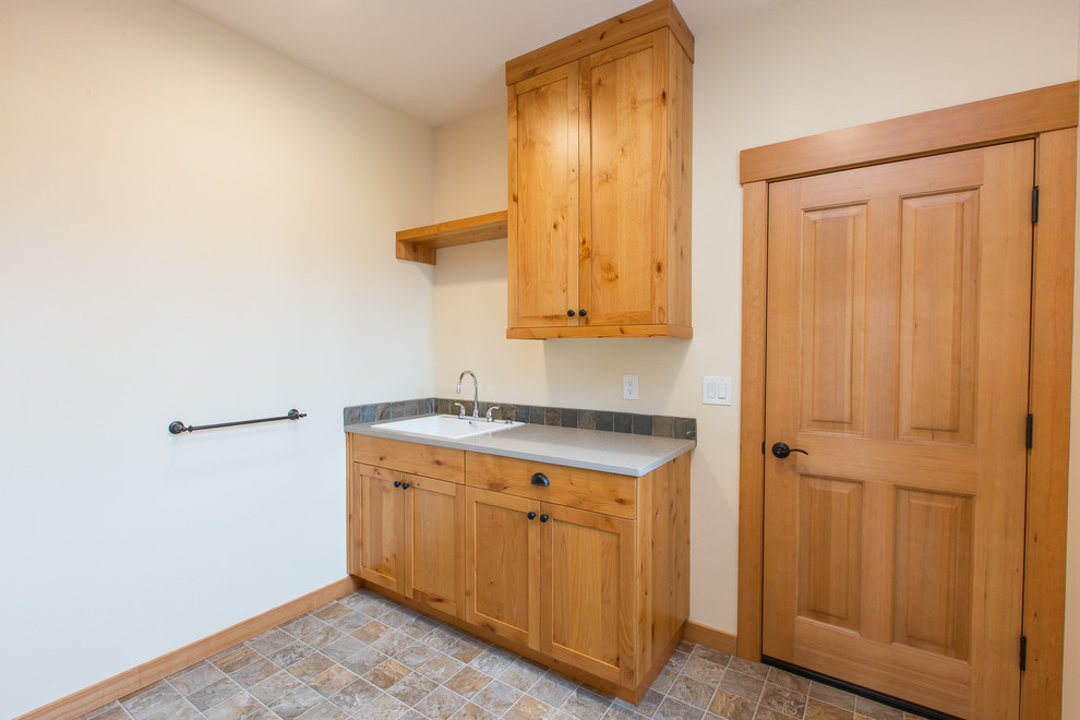 Immagine di una piccola sala lavanderia stile americano con ante in stile shaker, ante in legno chiaro, pareti beige, lavatrice e asciugatrice affiancate e lavello da incasso