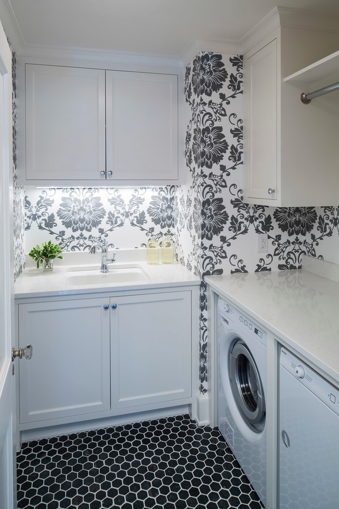 Inredning av en klassisk liten tvättstuga enbart för tvätt, med en undermonterad diskho, luckor med infälld panel, vita skåp, flerfärgade väggar, en tvättmaskin och torktumlare bredvid varandra och svart golv