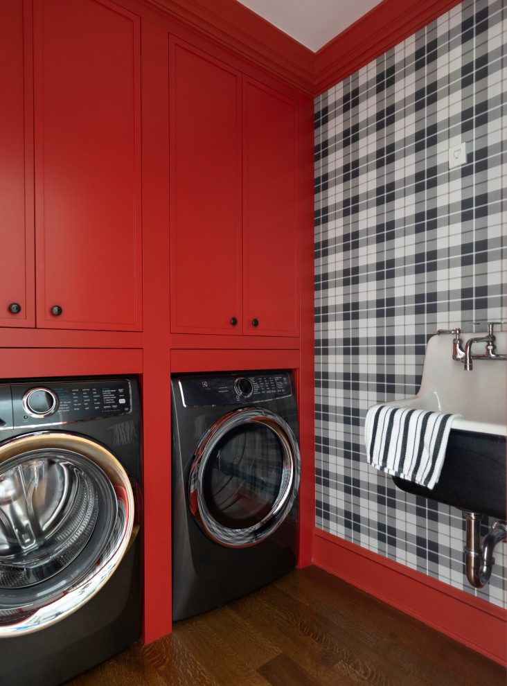 Exempel på en klassisk tvättstuga enbart för tvätt, med luckor med infälld panel, röda skåp, flerfärgade väggar, mörkt trägolv och en tvättmaskin och torktumlare bredvid varandra