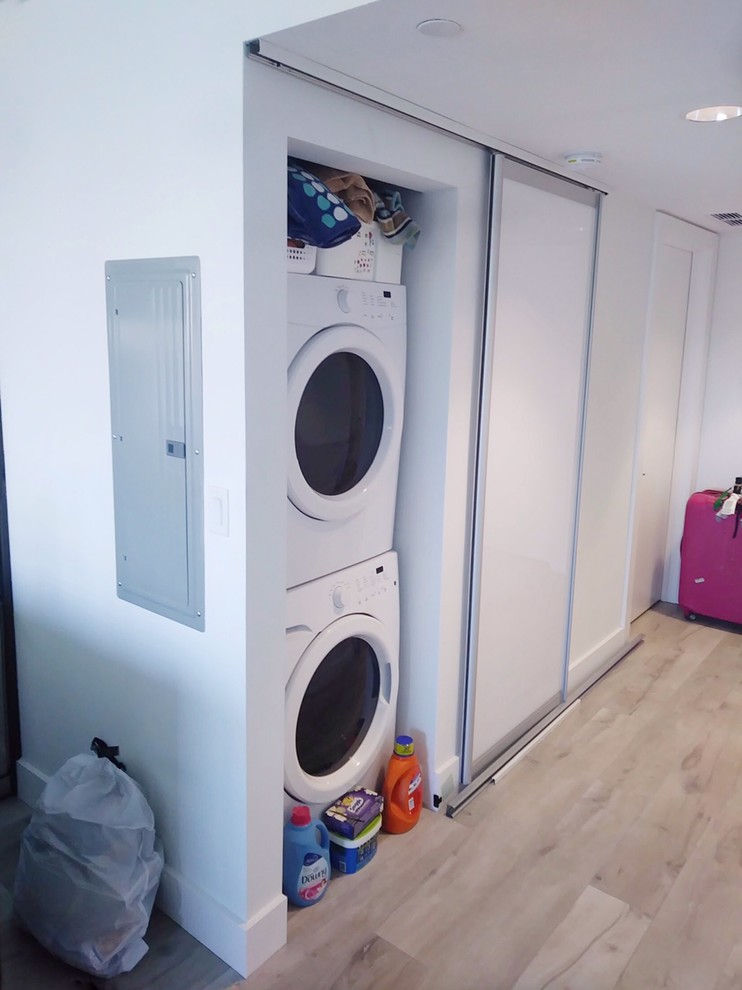 Imagen de armario lavadero de galera moderno pequeño con lavadora y secadora escondidas
