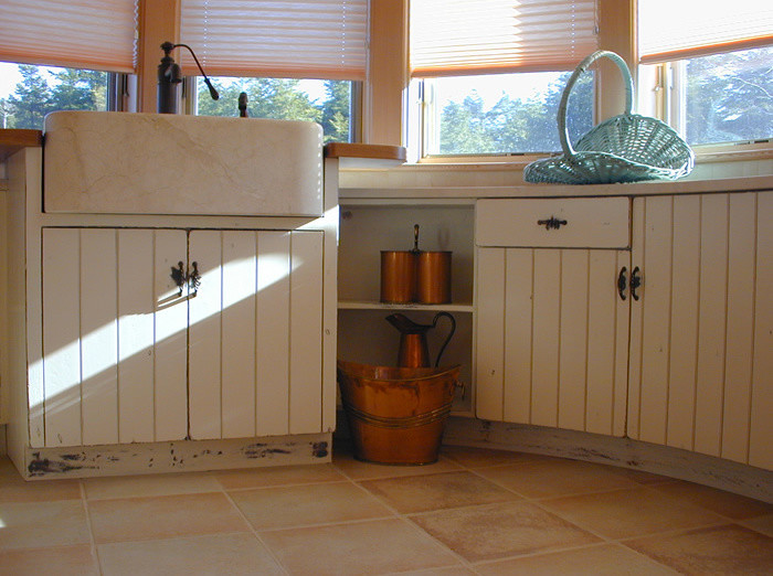 Cette image montre une buanderie chalet multi-usage et de taille moyenne avec un évier de ferme, un placard à porte shaker, des portes de placard blanches, un mur blanc et tomettes au sol.