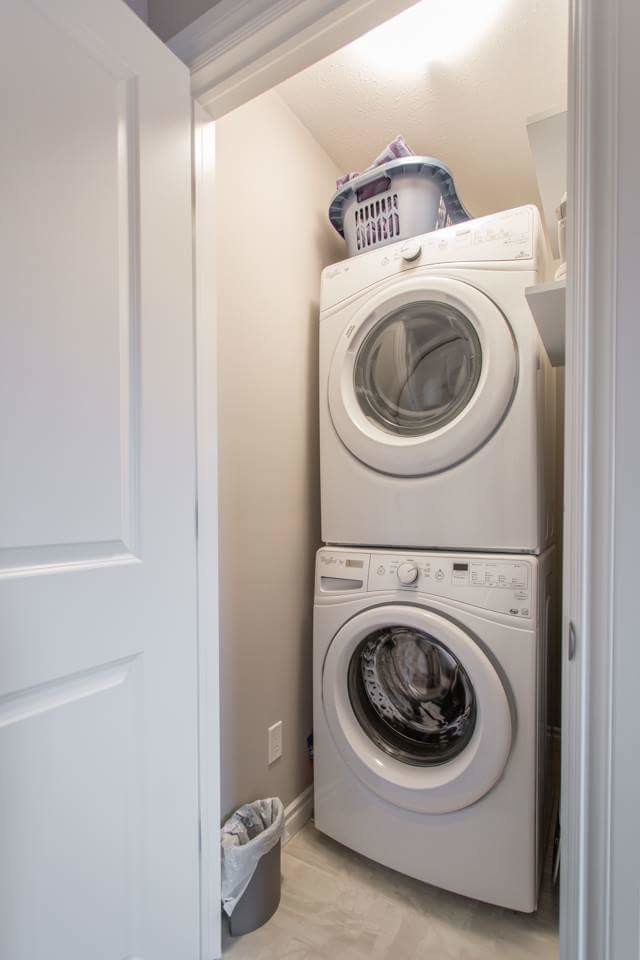 Einzeiliger, Kleiner Klassischer Hauswirtschaftsraum mit Waschmaschinenschrank, offenen Schränken, weißen Schränken, grauer Wandfarbe, Porzellan-Bodenfliesen, Waschmaschine und Trockner gestapelt und weißem Boden in Sonstige