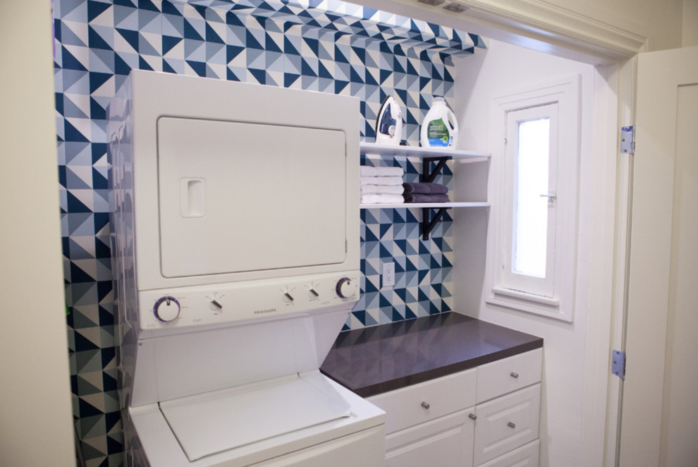 Inspiration for a medium sized contemporary galley laundry cupboard in San Francisco with flat-panel cabinets, white cabinets, engineered stone countertops, multi-coloured walls, a stacked washer and dryer and black worktops.