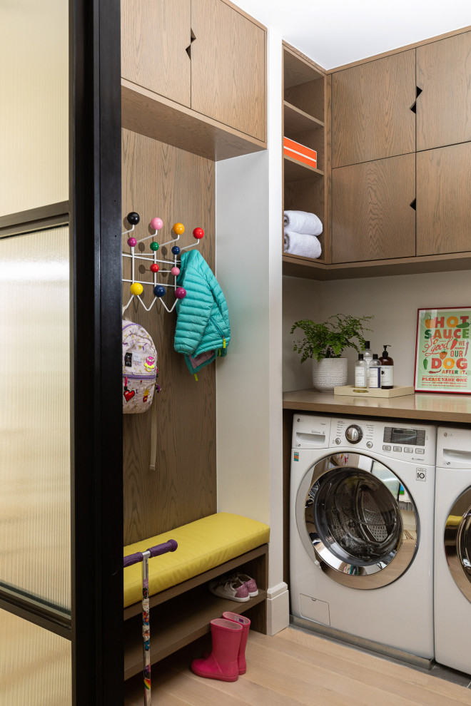 Immagine di una lavanderia minimal con ante lisce, ante in legno scuro, pareti bianche, parquet chiaro, lavatrice e asciugatrice affiancate e pavimento beige