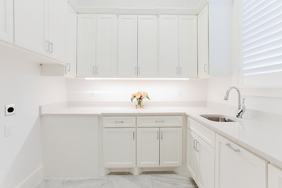 Foto di una lavanderia multiuso moderna di medie dimensioni con lavello sottopiano, ante in stile shaker, ante bianche, pareti bianche, pavimento in marmo e pavimento bianco