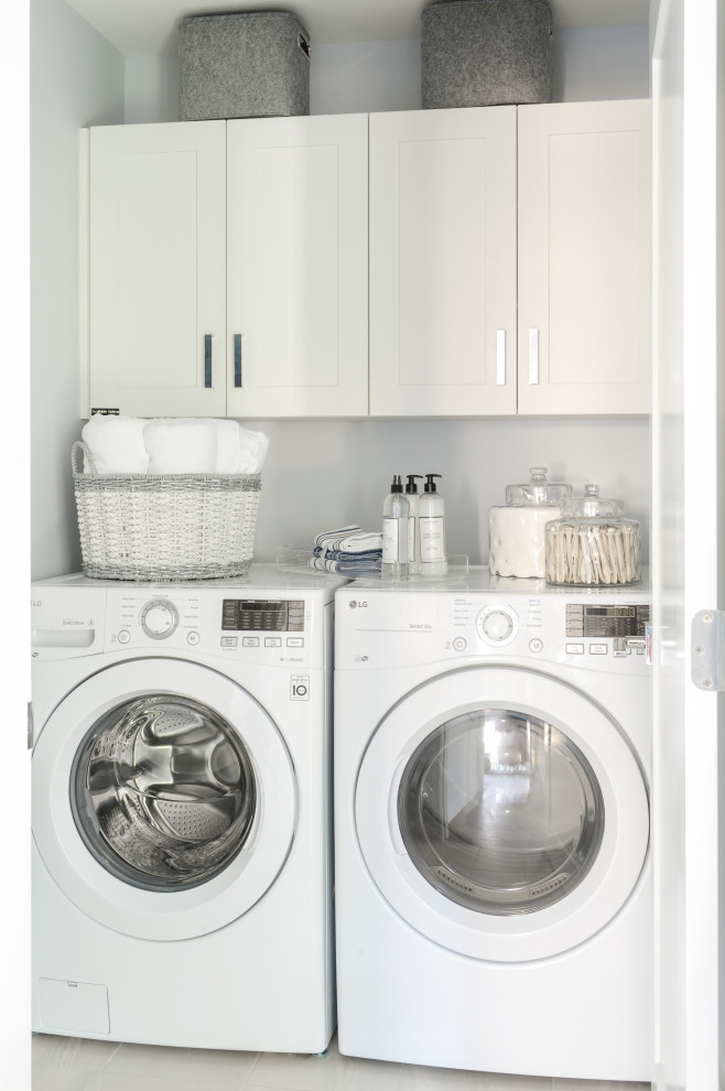 Klassisk inredning av en mellanstor vita linjär vitt tvättstuga enbart för tvätt, med luckor med infälld panel, vita skåp, en tvättmaskin och torktumlare bredvid varandra, en enkel diskho, bänkskiva i kvarts, klinkergolv i keramik, vitt golv och grå väggar