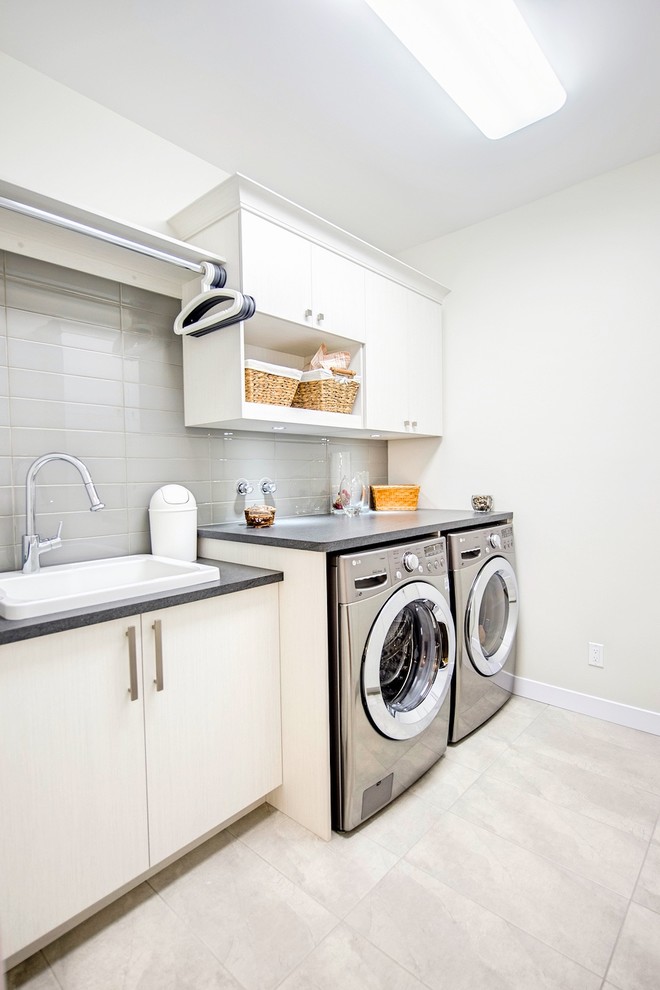 Exempel på en stor modern grå parallell grått tvättstuga enbart för tvätt, med en nedsänkt diskho, släta luckor, vita skåp, bänkskiva i koppar, vita väggar, klinkergolv i keramik, en tvättmaskin och torktumlare bredvid varandra och grått golv