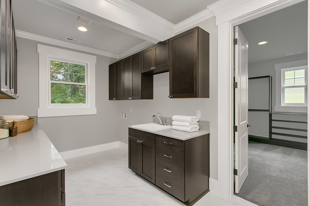 Design ideas for a large traditional single-wall separated utility room in Seattle with flat-panel cabinets, dark wood cabinets, quartz worktops, grey walls, porcelain flooring, a side by side washer and dryer and a built-in sink.