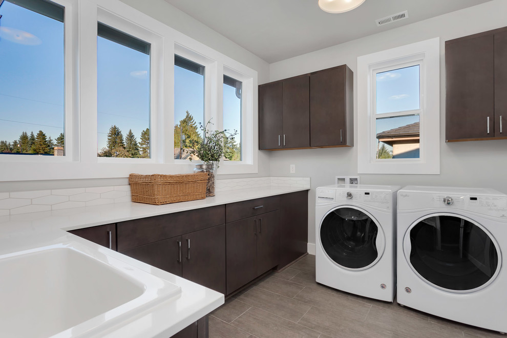 Large trendy l-shaped gray floor dedicated laundry room photo in Seattle with an utility sink, flat-panel cabinets, dark wood cabinets, quartz countertops, gray walls and a side-by-side washer/dryer