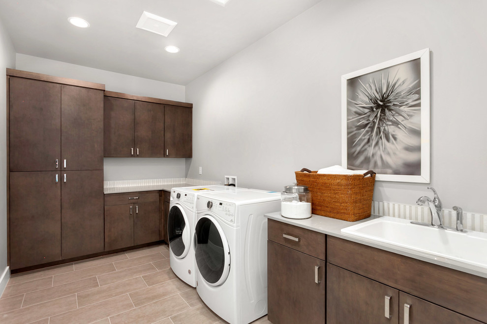 Idee per una grande sala lavanderia contemporanea con lavatoio, ante lisce, ante in legno bruno, top in quarzo composito, pareti grigie, lavatrice e asciugatrice affiancate e pavimento grigio