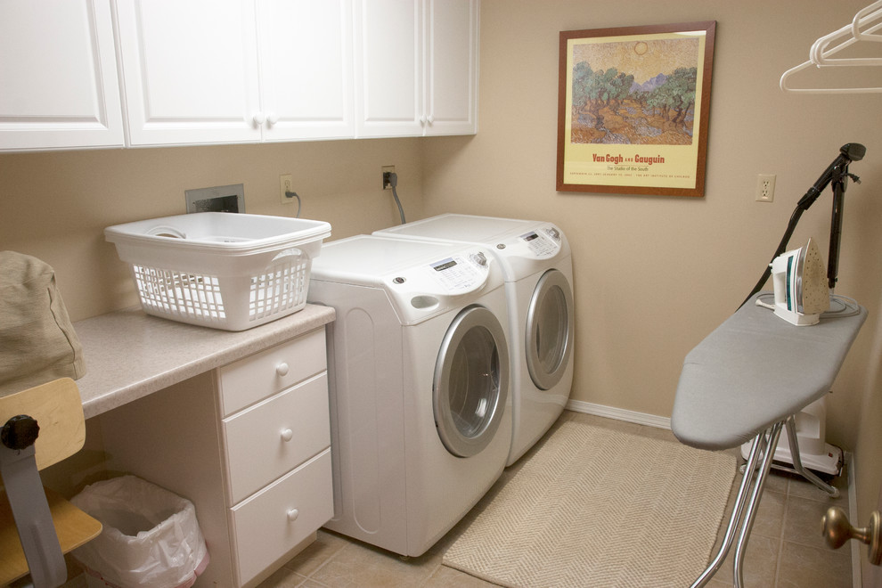 Exempel på en liten eklektisk u-formad tvättstuga enbart för tvätt, med skåp i shakerstil, vita skåp, beige väggar, klinkergolv i keramik och en tvättmaskin och torktumlare bredvid varandra