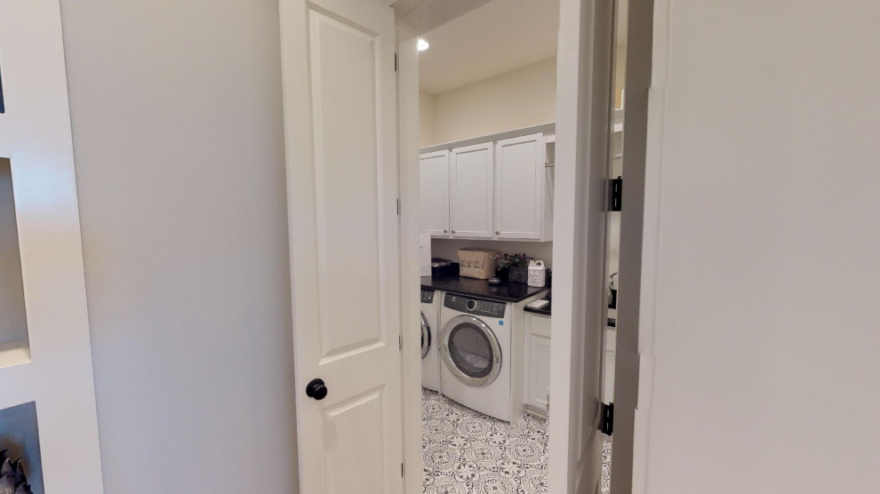 Example of a small cottage single-wall ceramic tile and black floor dedicated laundry room design in Atlanta with an undermount sink, shaker cabinets, white cabinets, quartz countertops, white walls, a side-by-side washer/dryer and black countertops