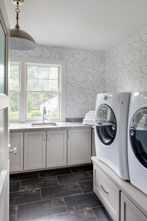 mid-sized transitional l-shaped ceramic tile and black floor laundry room design in Boston with granite countertops, a side-by-side washer/dryer, an undermount sink, shaker cabinets, white cabinets, white walls and gray countertops