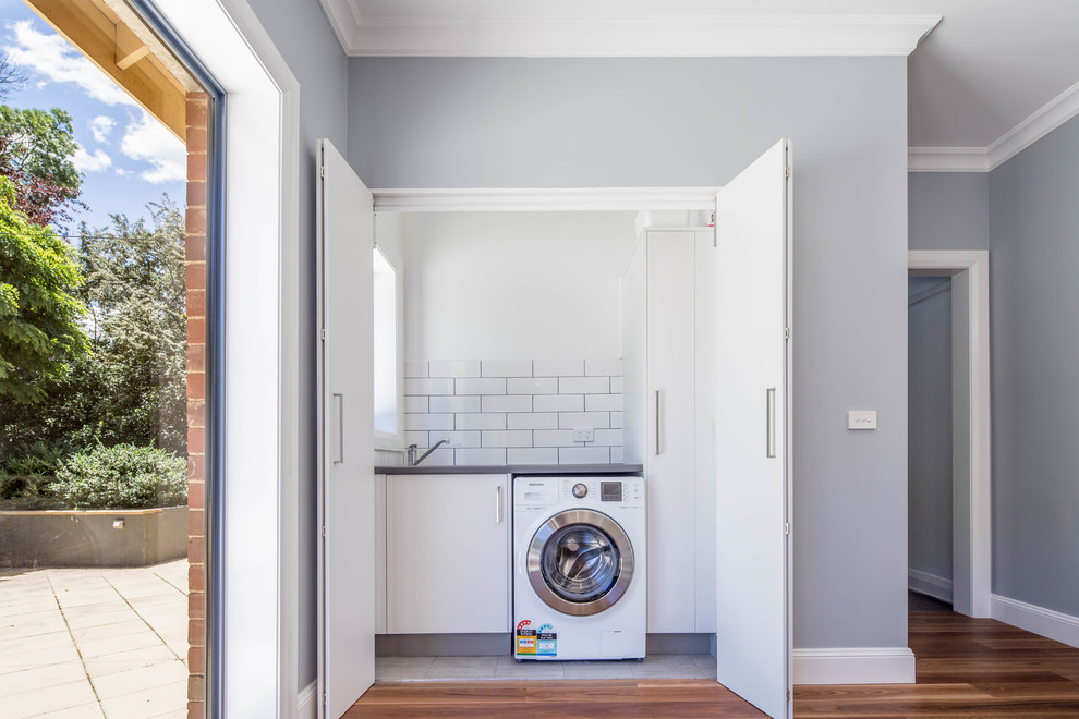 Ejemplo de armario lavadero lineal nórdico pequeño con encimera de laminado, paredes blancas, suelo de baldosas de porcelana y suelo gris
