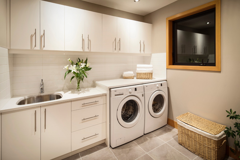 Photo of a medium sized contemporary galley separated utility room in Vancouver with flat-panel cabinets, white cabinets, granite worktops, white walls, ceramic flooring, a side by side washer and dryer and a submerged sink.